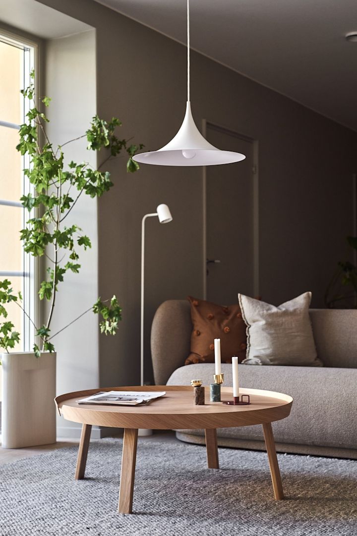 Belysningsidéer för vardagsrummet inkluderar den hängande taklampan Semi från Gubi med sin böjda skärm som ses här hängande över ett soffbord. 