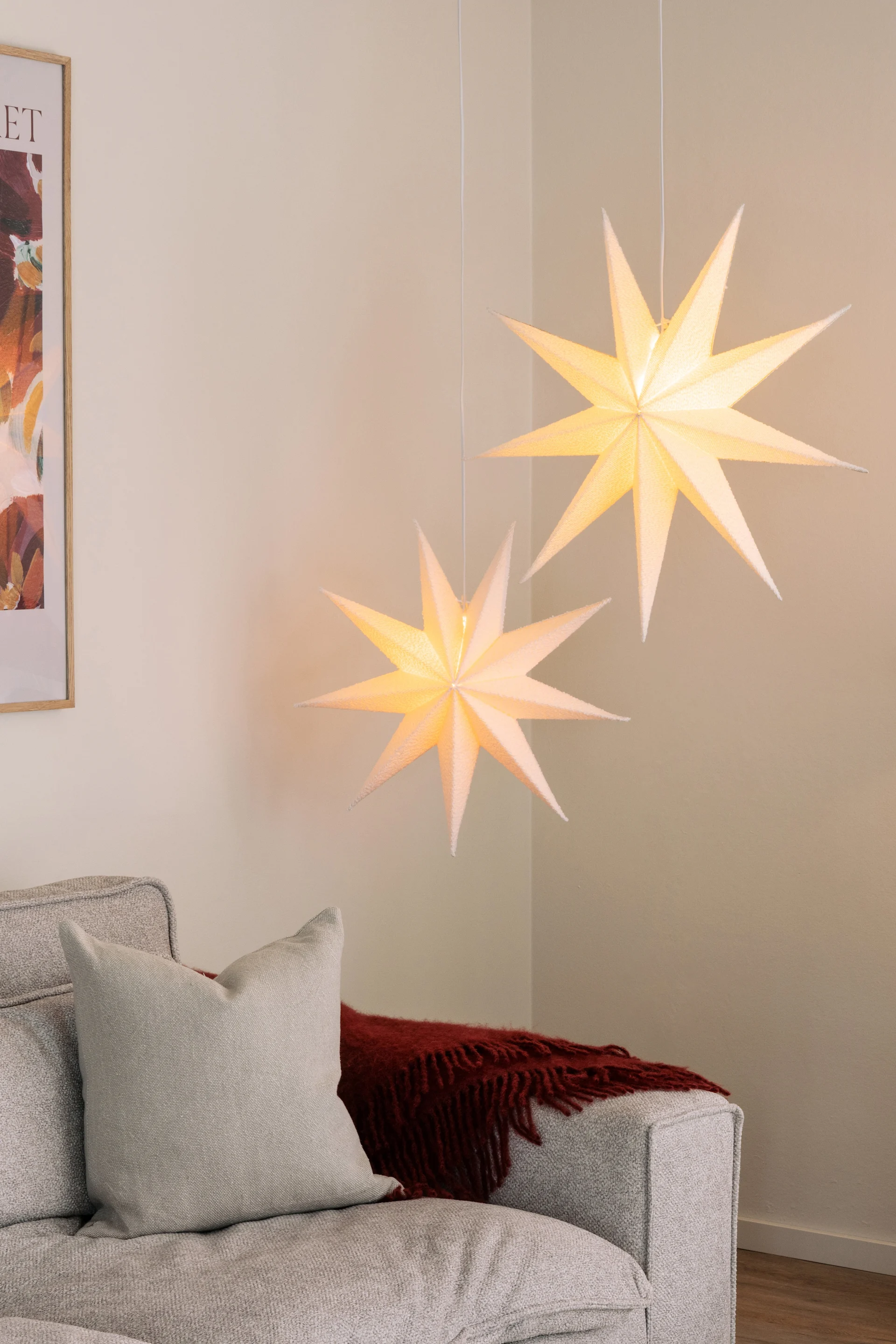 The Stella Boucle paper star lantern from Globen lighting hangs in a pair in a living room above a sofa. 