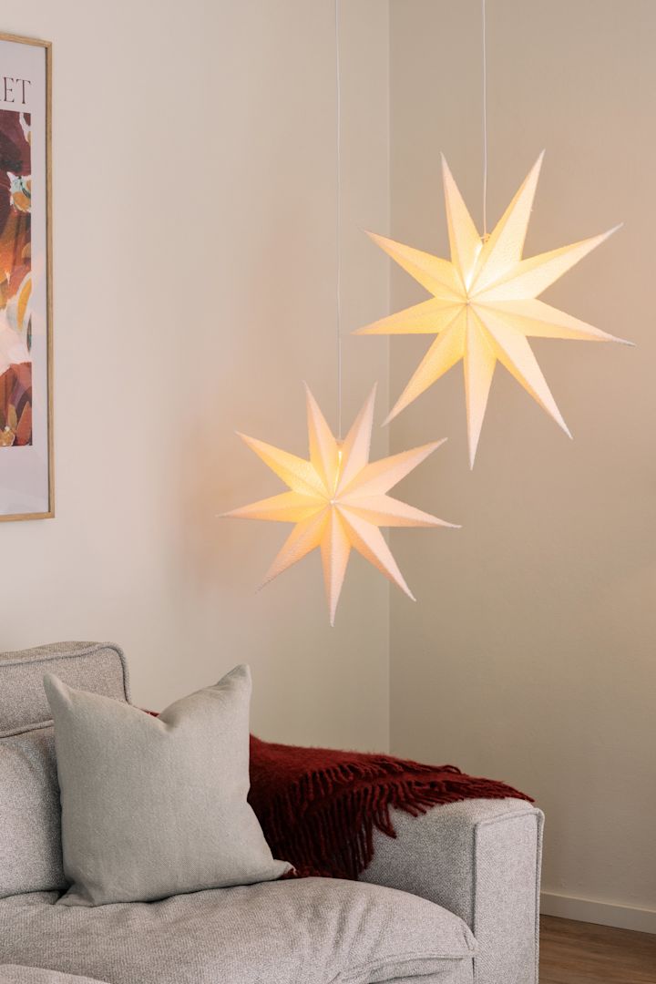 The Stella Boucle paper star lantern from Globen lighting hangs in a pair in a living room above a sofa. 