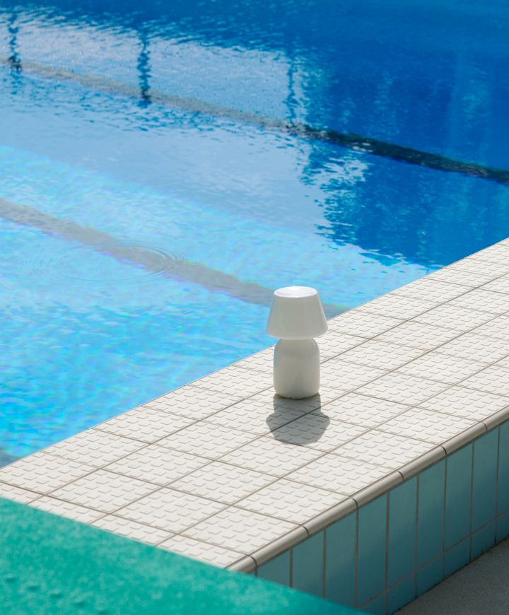 Den portabla Apollo-lampan från HAY står bredvid en pool. 